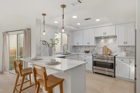 a kitchen with kitchen island a stove a table and chairs in it