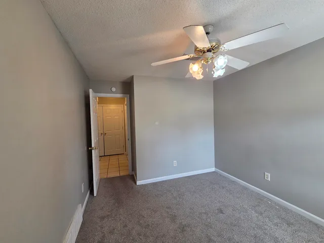 an empty room with closet and a chandelier fan
