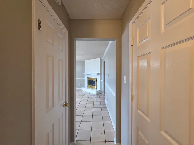 a view of a hallway with wooden floor and a bathroom