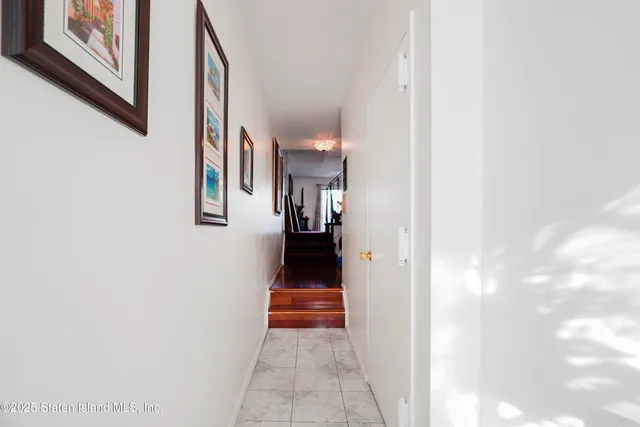 a view of a hallway with wooden floor and a bathroom