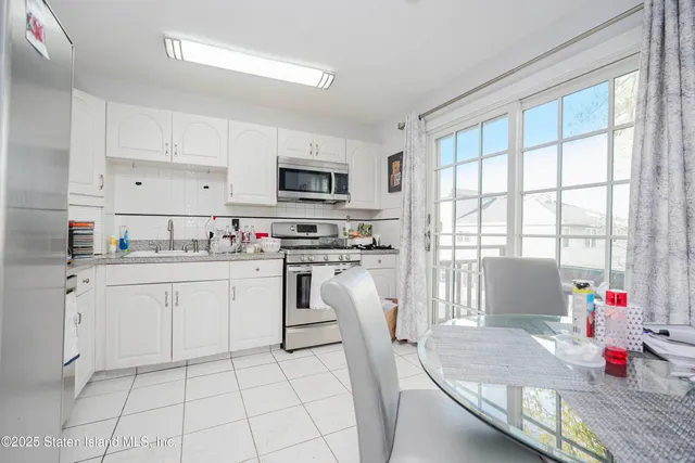 a kitchen with white cabinets appliances and a window