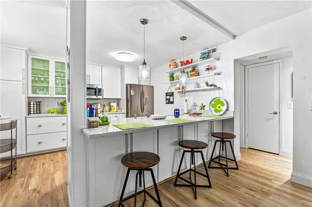 a kitchen with stainless steel appliances a center island table and chairs in it