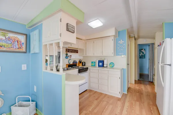 a kitchen with white cabinets and wooden floor