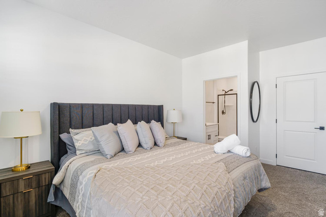 1705 Ripple Rock Drive, Unit 3017 Washington, UT 84780 - Photo 8 of 22 Carpeted room with white walls, featuring a dark upholstered headboard, wood-finish nightstand, white paneled door with dark hardware, and a recessed bathroom entry with shower