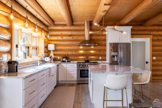 a large kitchen with kitchen island a large counter top space a sink stainless steel appliances and cabinets