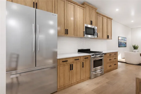 a kitchen with stainless steel appliances granite countertop a refrigerator a stove and a sink with wooden floor