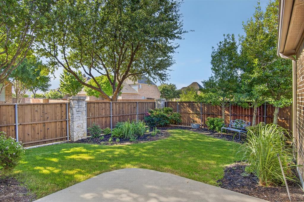 842 Sun Meadow Road Allen, TX 75013 - Photo 31 of 39 Expansive backyard featuring a manicured lawn, established landscaping beds, a wood privacy fence with stone pillars, and mature trees providing natural shade