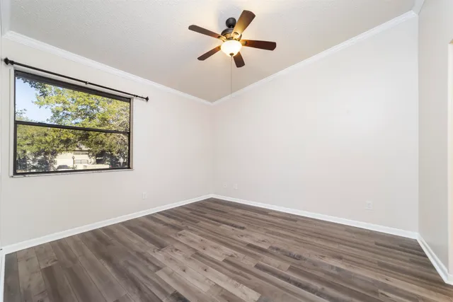 an empty room with wooden floor closet and windows