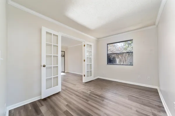 an empty room with wooden floor closet and windows