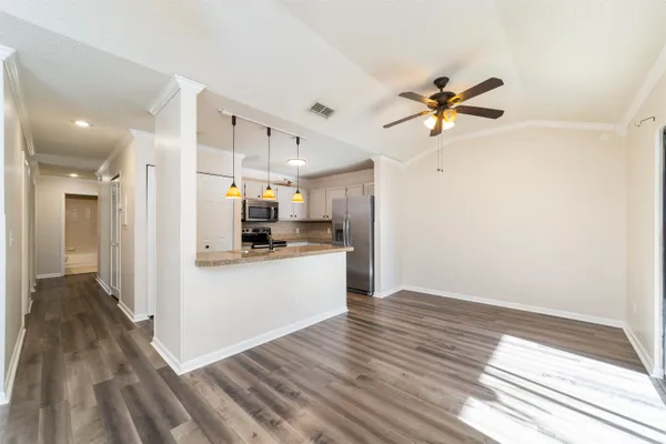 a view of kitchen with stainless steel appliances granite countertop a refrigerator a sink dishwasher a stove and white countertops with wooden floor