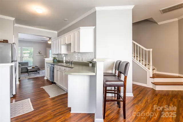 a living room with stainless steel appliances kitchen island granite countertop furniture and a wooden floor