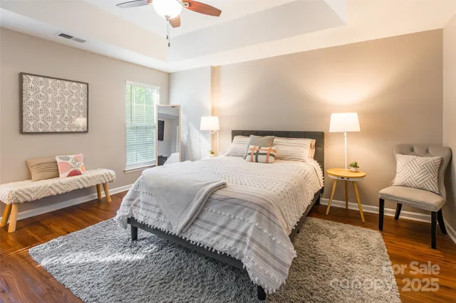 a bedroom with a bed a couch and a dresser with wooden floor