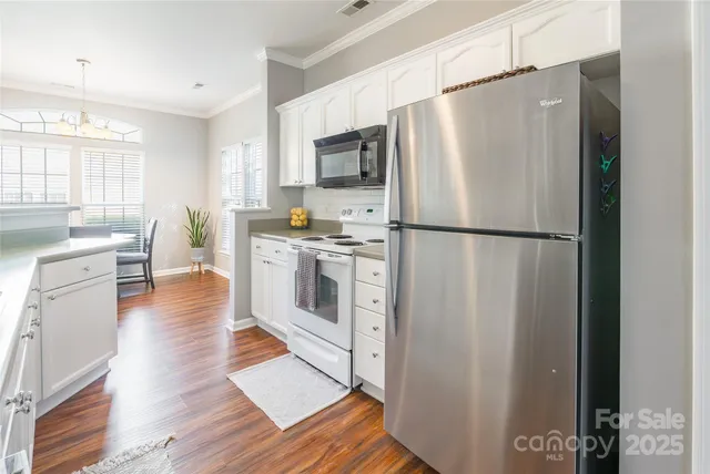 a kitchen with stainless steel appliances a refrigerator a stove a sink cabinets and a dining table