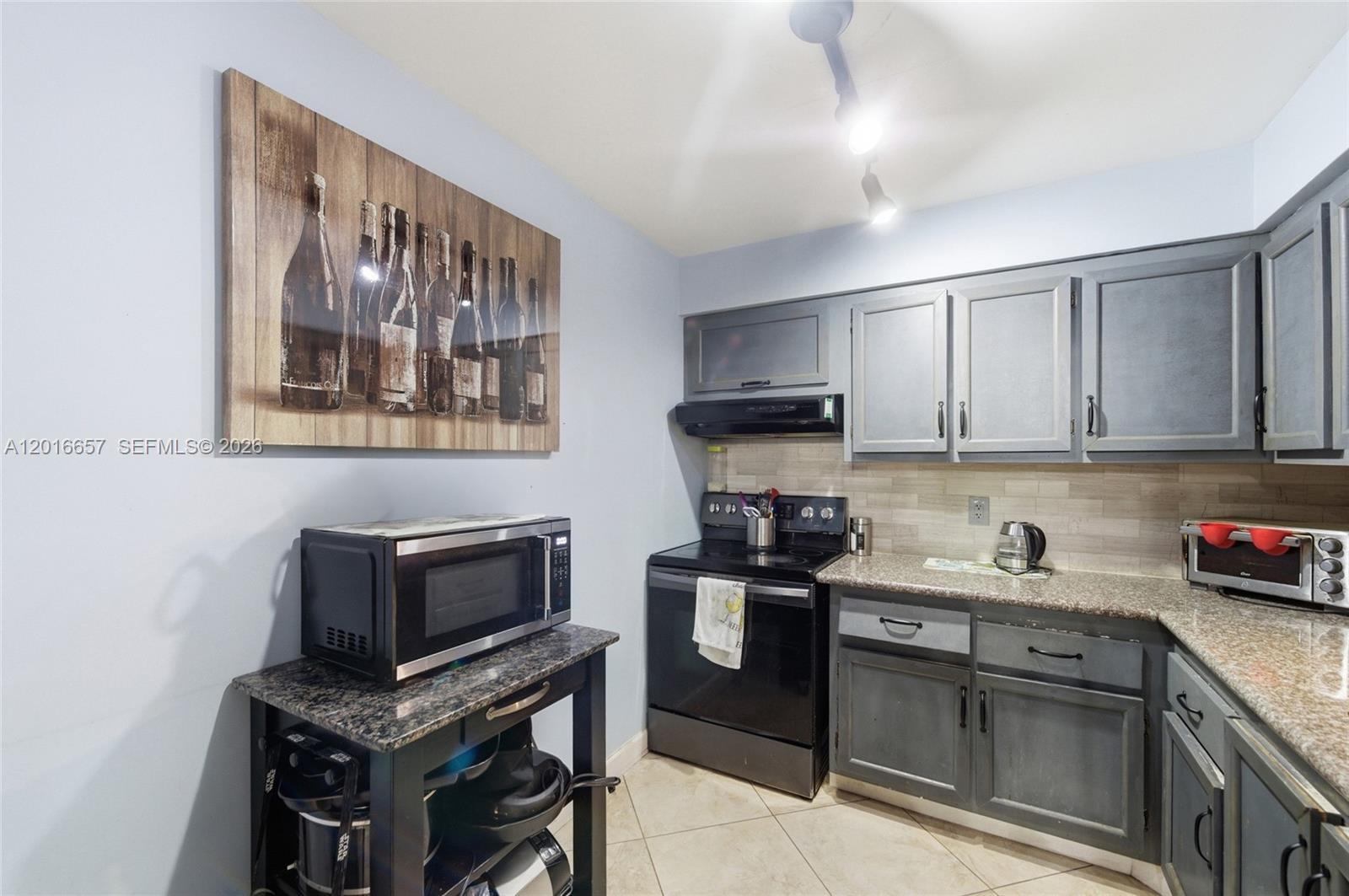 6195 Rock Island Road, Unit 511 Tamarac, FL 33319 - Photo 12 of 31 a kitchen with stainless steel appliances a stove sink microwave and cabinets