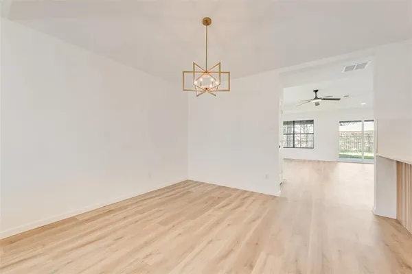 a view of empty room with wooden floor and ceiling fan