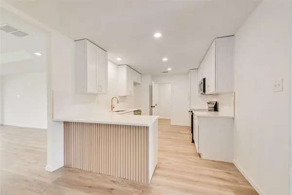 a kitchen with kitchen island a sink a stove a refrigerator and white cabinets