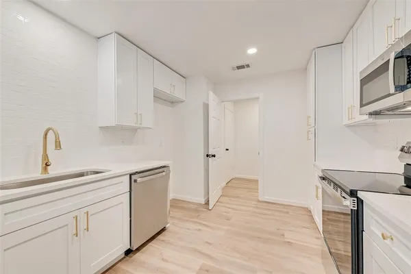 a kitchen with white cabinets and sink