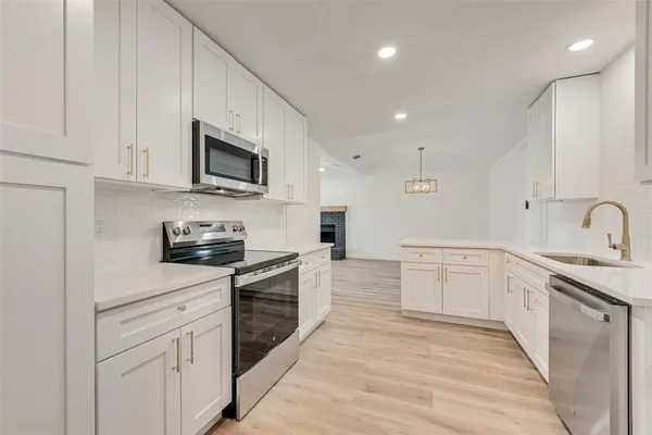 a kitchen with stainless steel appliances granite countertop a stove top oven a sink dishwasher and a microwave oven with white cabinets