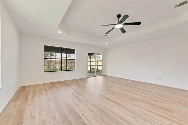 a view of empty room with wooden floor and ceiling fan