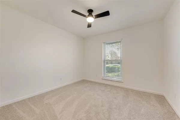 an empty room with ceiling fan and windows
