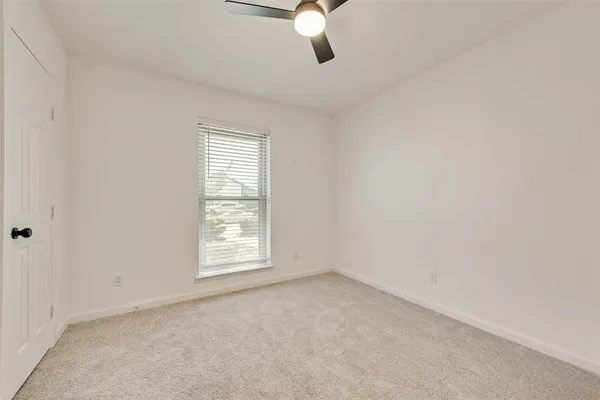 an empty room with windows and chandelier fan