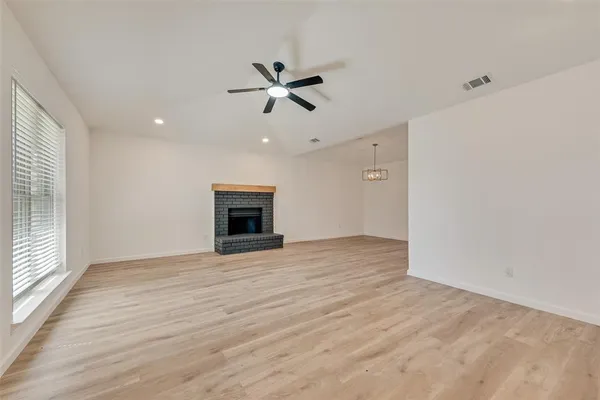 an empty room with windows and fireplace