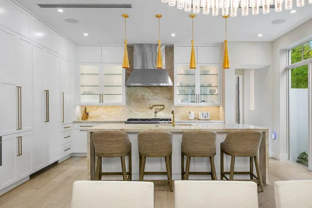 a kitchen with stainless steel appliances granite countertop a table chairs sink and cabinets