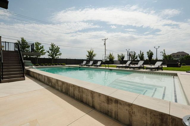 924 Country Lane Farmington, UT 84025 - Photo 71 of 91 Expansive outdoor pool area featuring a concrete deck, integrated steps, and a perimeter fence