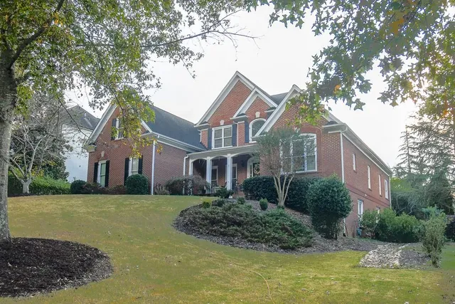 a front view of a house with a garden and tree