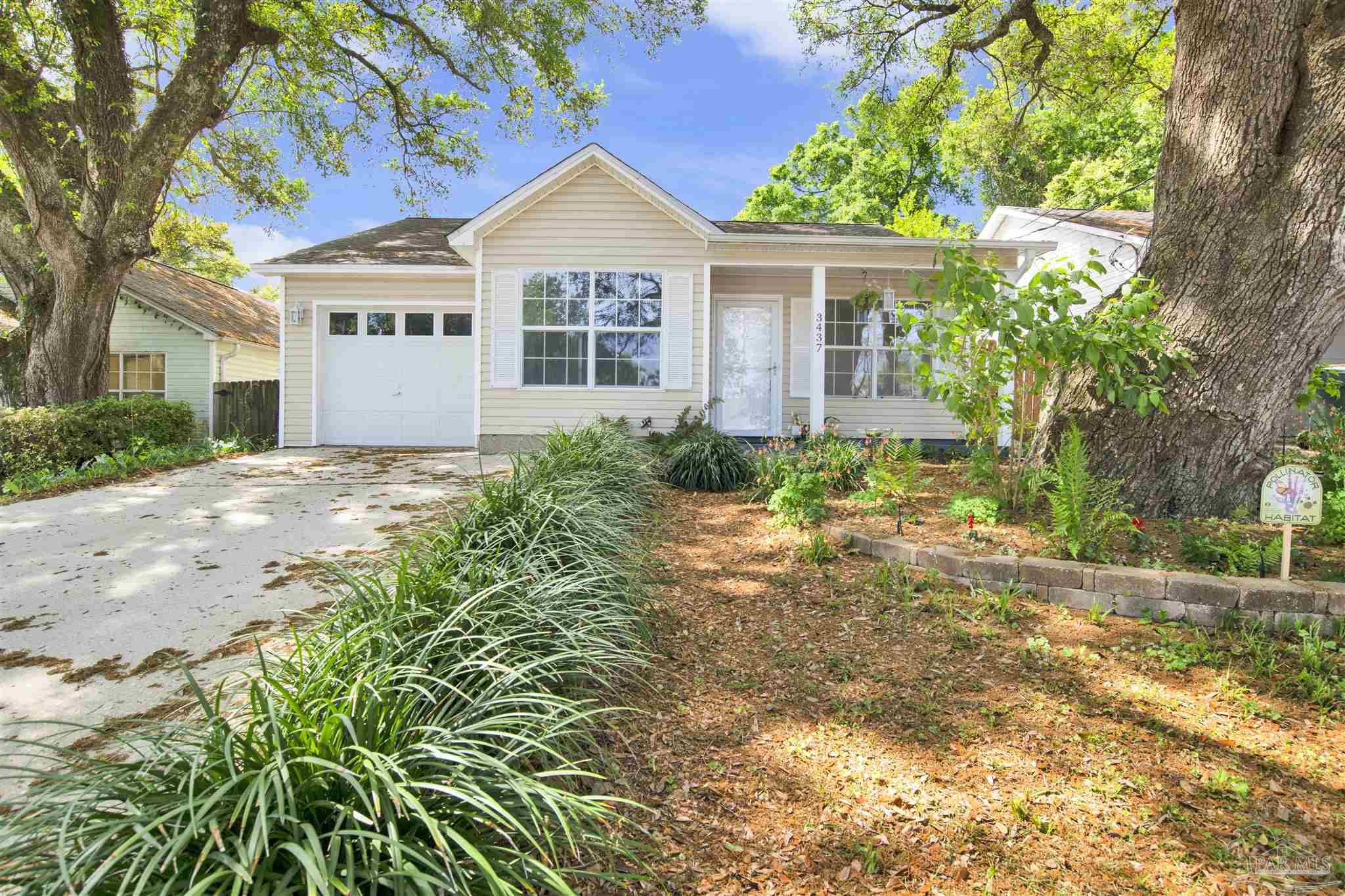 a view of a house with a small yard and a large tree