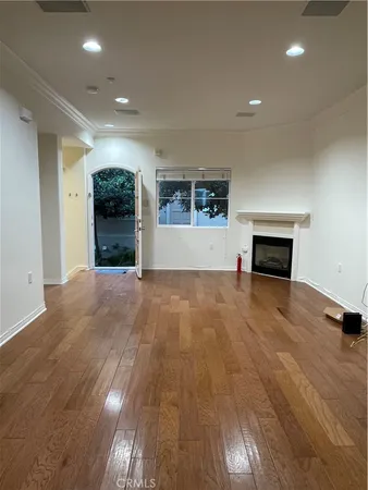 an empty room with wooden floor a fireplace and window