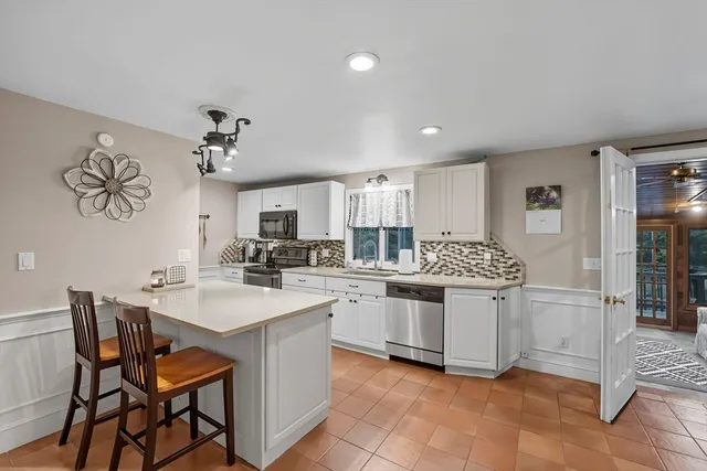 a kitchen with stainless steel appliances a sink a stove a refrigerator dining table and chairs