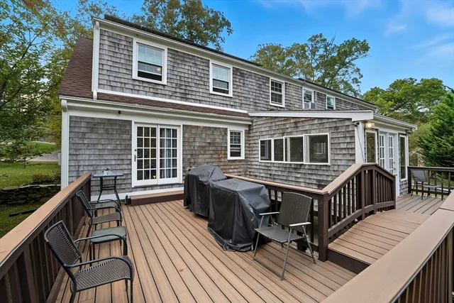 a balcony of a house with wooden floor outdoor seating and yard in the back