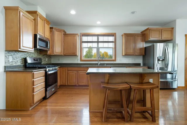 a kitchen with stainless steel appliances granite countertop wooden cabinets a stove top oven a sink and dishwasher with wooden floor