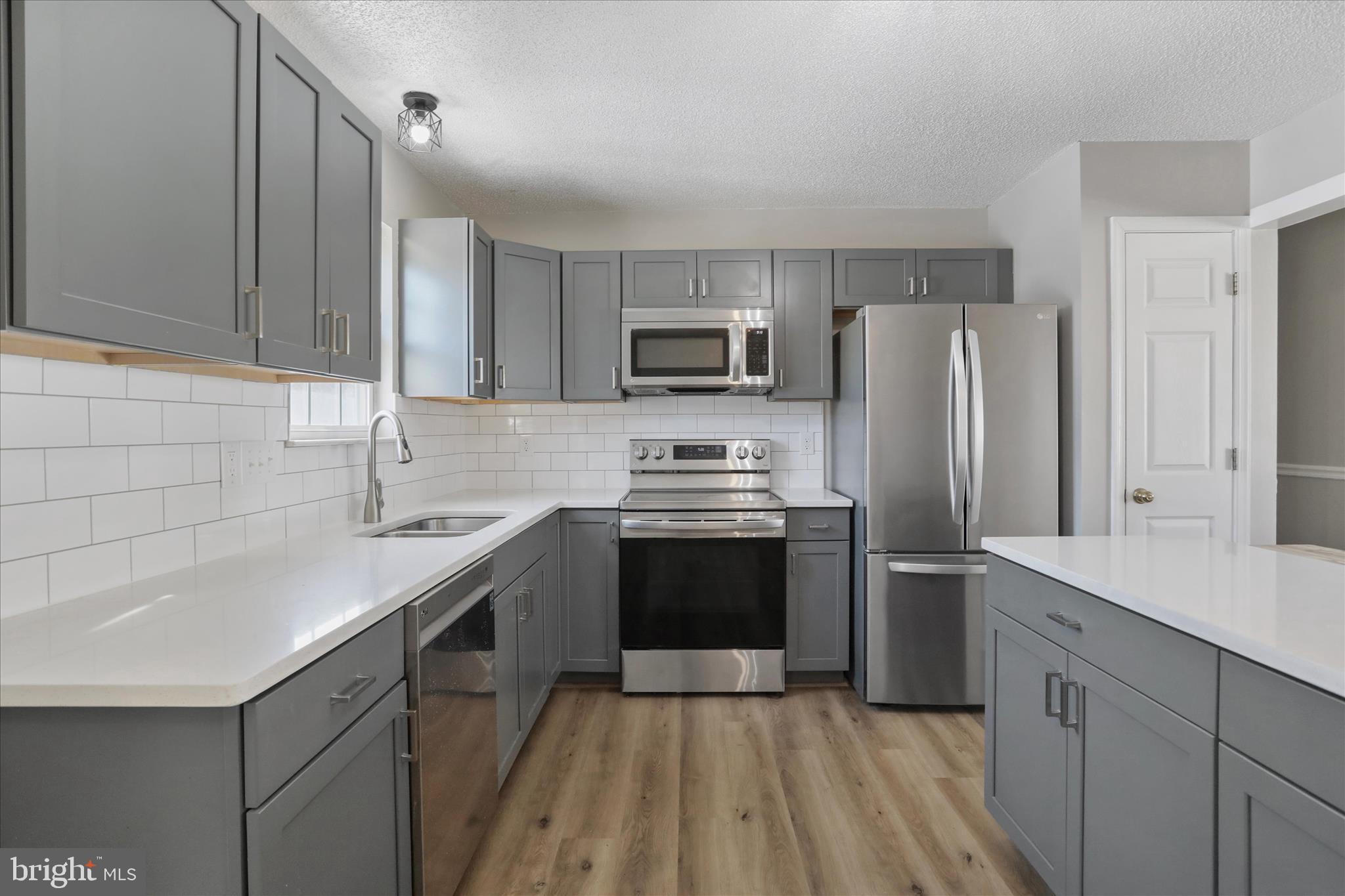 137 Woodrow Road Winchester, VA 22602 - Photo 14 of 45 a kitchen with a sink a refrigerator and a stove top oven with wooden floor