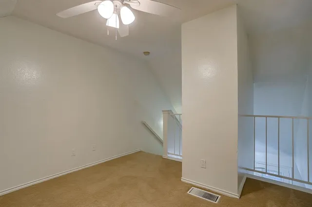 an empty room with a fan & a ceiling fan