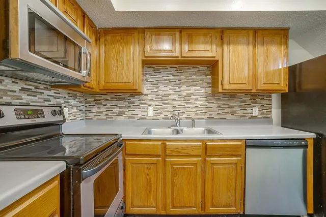 a kitchen with stainless steel appliances granite countertop a refrigerator a stove a sink and a microwave