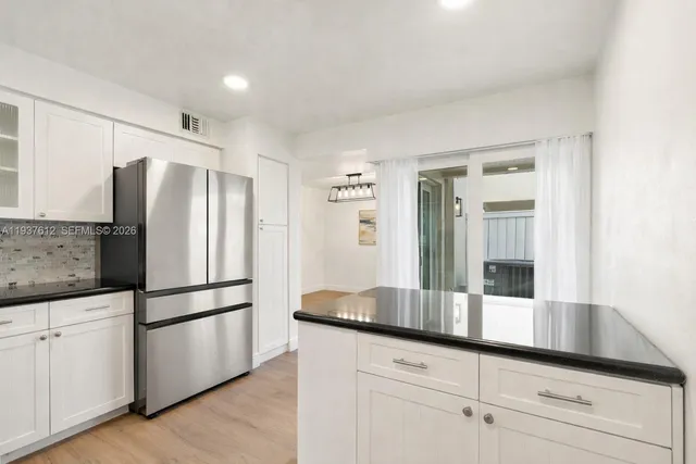 a kitchen with granite countertop a refrigerator and cabinets