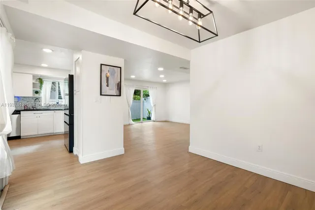 a view of a kitchen and a hallway with wooden floor