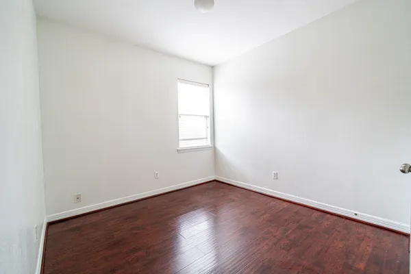 an empty room with wooden floor and window