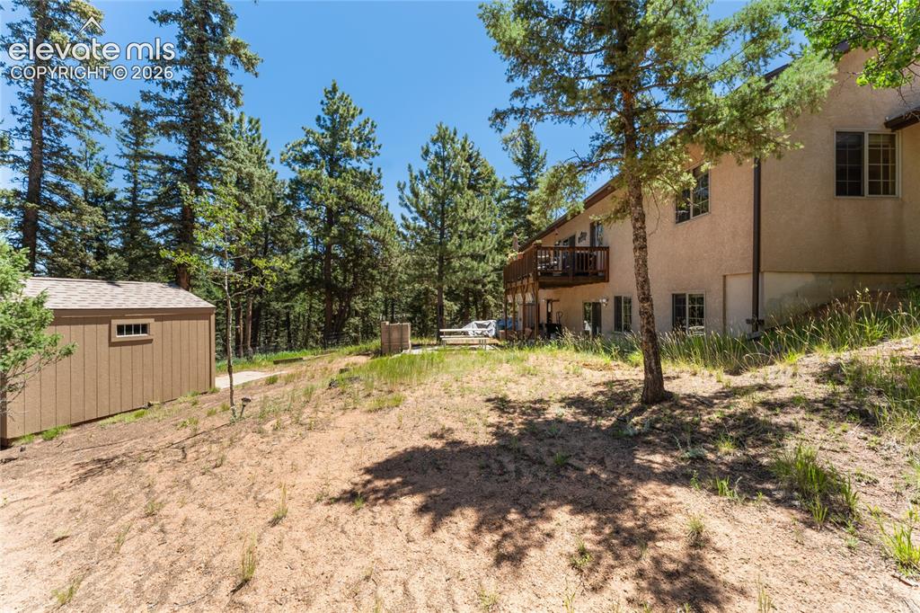 657 Spring Valley Drive Divide, CO 80814 - Photo 39 of 43 Stucco exterior dwelling with a tiered wooden deck, surrounded by mature pine trees