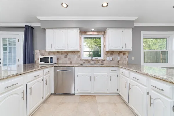 a kitchen with stainless steel appliances granite countertop a stove a sink a dining table and chairs