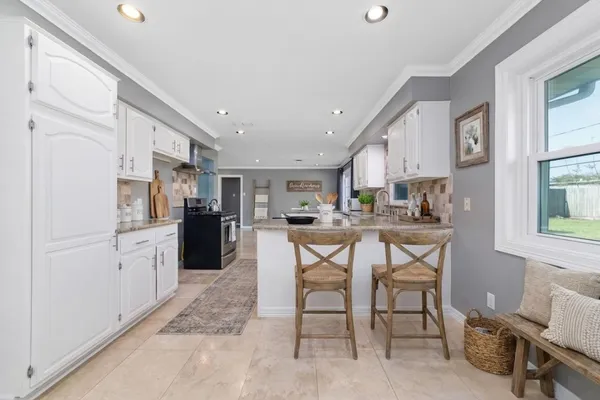 a kitchen with white cabinets appliances a sink and a window