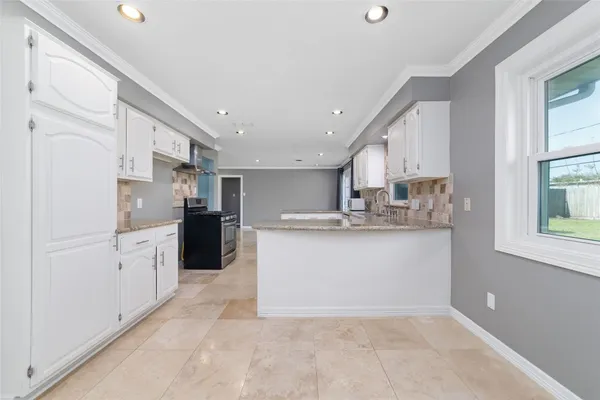 a kitchen with stainless steel appliances kitchen island granite countertop a refrigerator a stove a sink a dining table and chairs with wooden floor