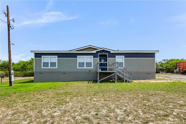 a house that is sitting in the grass with large trees