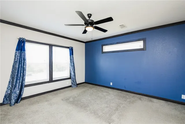 an empty room with windows and ceiling fan