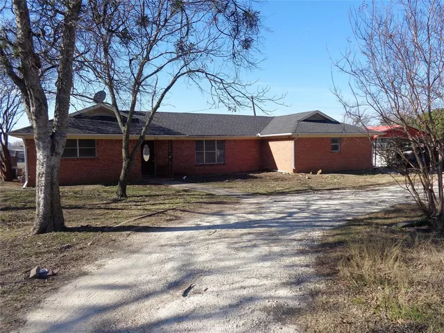 a front view of a house with a yard and large tree