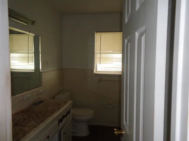 a bathroom with a granite countertop sink a toilet and a window