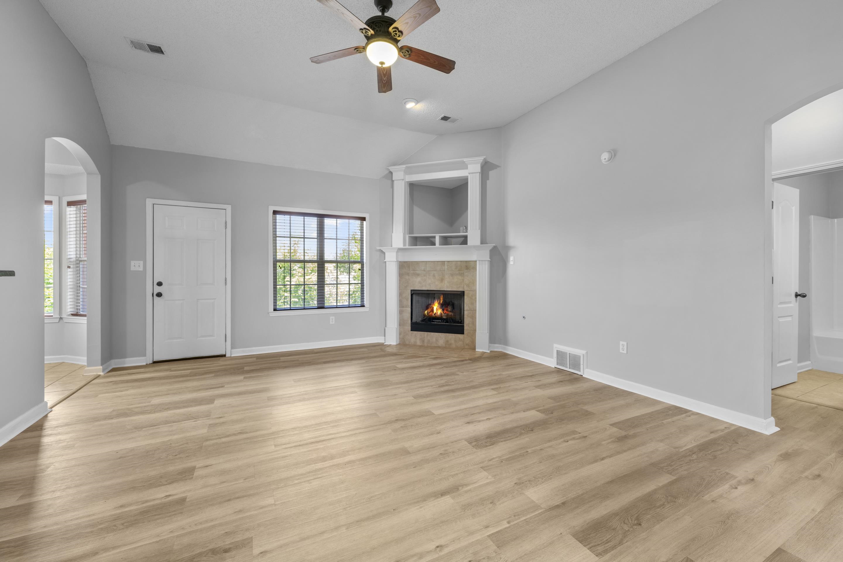 50 Abbey Road Oakland, TN 38060 - Photo 5 of 26 Spacious living area featuring vaulted ceilings, wood-finish flooring, and a corner fireplace with a tiled surround and mantel