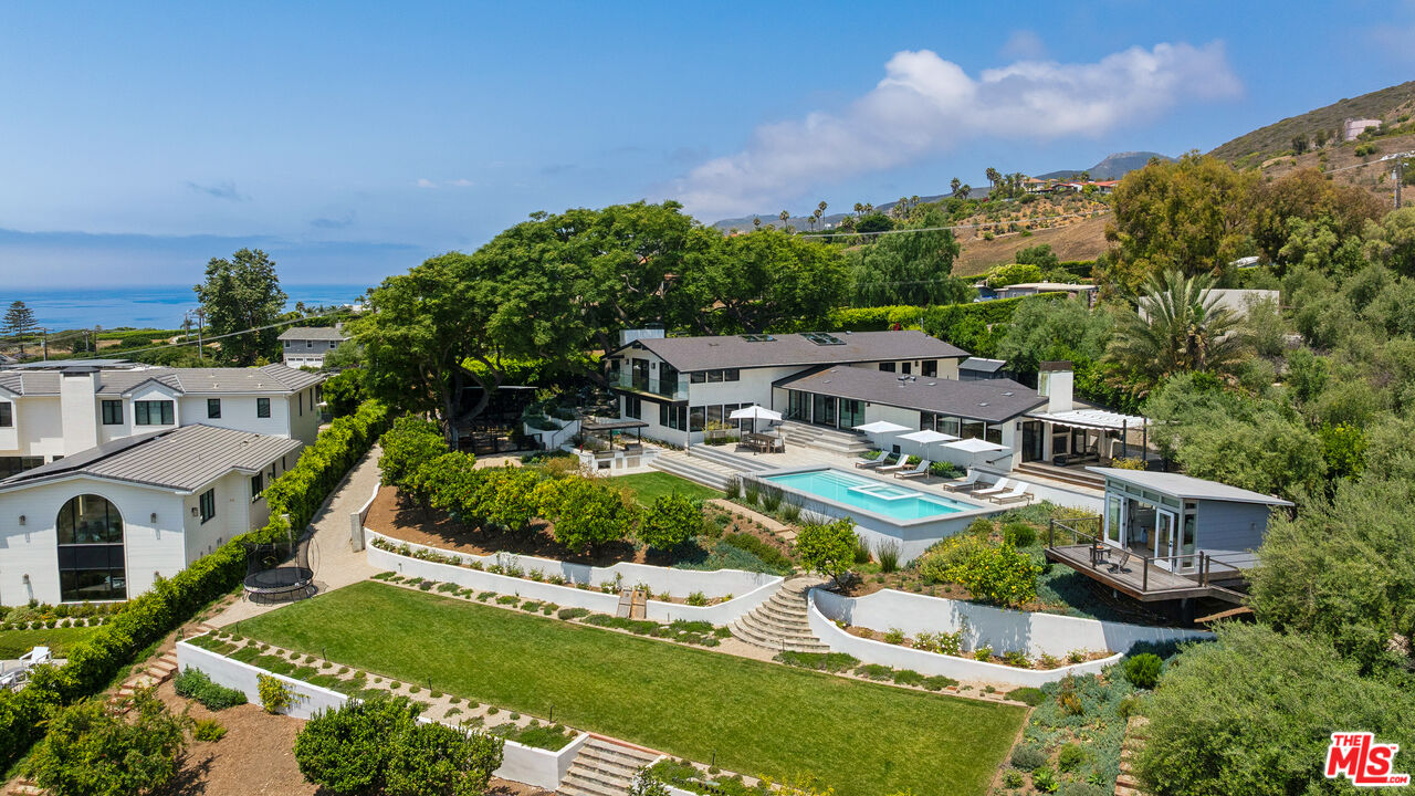 an aerial view of residential houses with outdoor space and trees all around